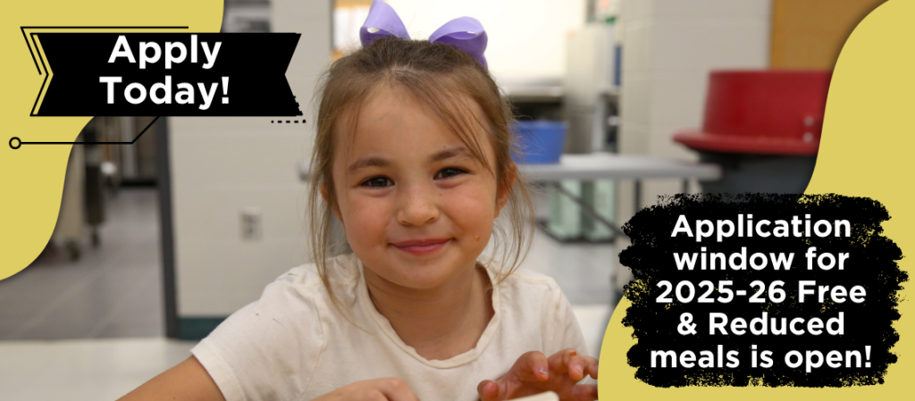 A young girl is smiling at the camera in front of a school building.