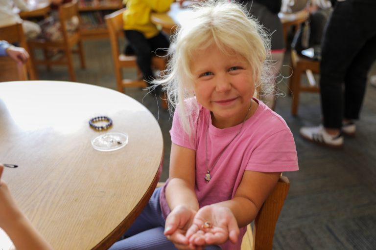 Young girl in pink shirt holding a small glass dome.