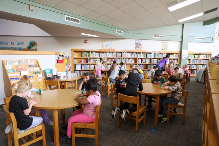 Children sitting at tables in a library.