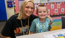 Teacher in kindergarten t-shirt with smiling kindergarten student