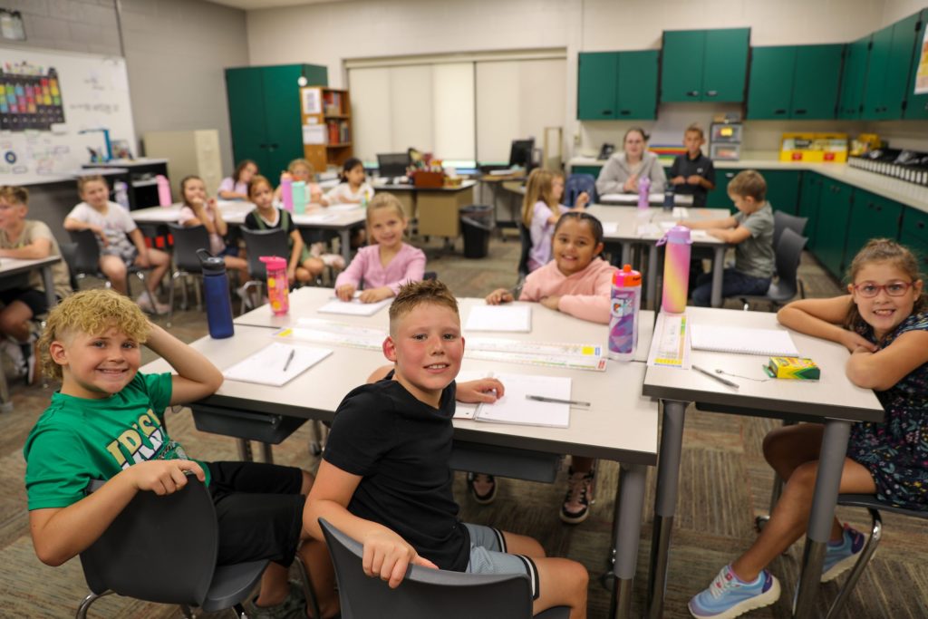 A group of students sitting at desks in a classroom, engaged in an activity